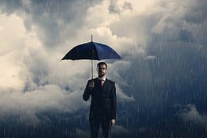 a man with umbrella standing over stormy background. Make disaster recovery plan a top priority